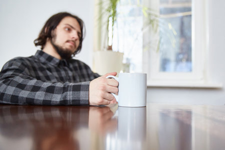 A cup of tea or coffee in the hands of a young man. Focus on the cup.の写真素材
