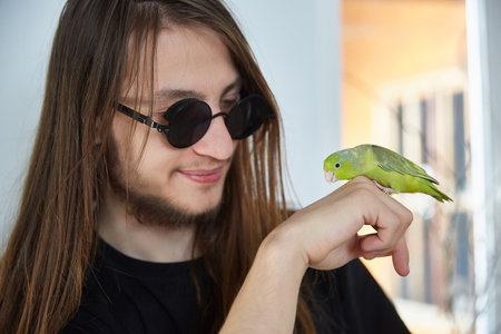A guy with long hair communicates with a parrot forpusの写真素材