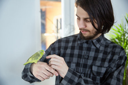 A young man interacts with a pet parrot forpusの写真素材