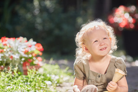 A cheerful child with ice cream in his hands. In the sunshine on a hot summer dayの写真素材