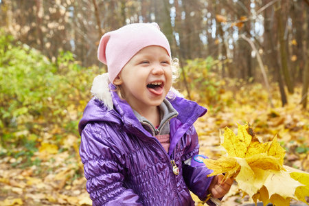 girl is sitting on a fallen tree log in the autumn sunny yellow forestの写真素材