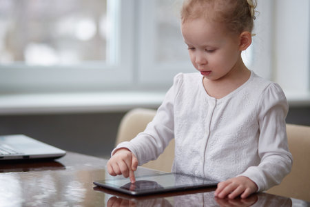 A preschooler girl uses a tablet for learning and entertainment. Modern education. Copy spaceの写真素材