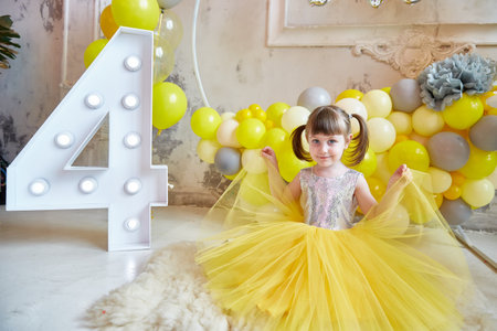 girl in a yellow dress against a background of yellow balloons. Birthday decor. Room decoration. photozone for invitation, festival, birthday conceptの写真素材