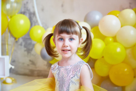 Funny family on a background of bright blue wall. Mother and her daughter girl are having fun with balloons and confetti. Yellow, pink and turquoise colors.の写真素材