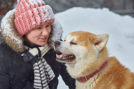 A woman in a snowy winter with an akita dog. Close-upの写真素材