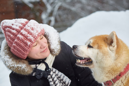 A woman with an akita dog. sports and outdoor recreation on a snowy winter day. Close-up.の写真素材