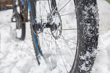A bicycle wheel with winter spikes in the snow on a winter road.の写真素材