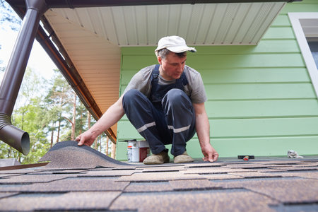 A worker installs a soft roof on the roof of a country house. Made of modified bitumen and stone chips based on fiberglass.の写真素材