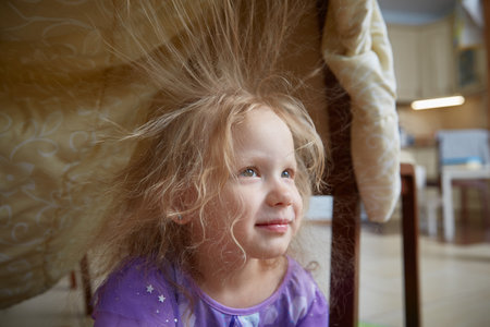 A child at home plays in a house built from a blanket.の写真素材