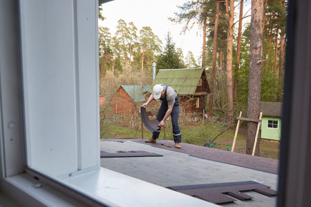 A worker makes a roof. View from the window