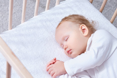 The baby sleeps safely and sweetly wooden crib on a terry sheet elastic band.の写真素材