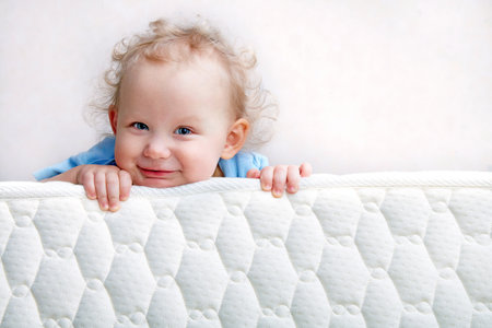 Baby on the bed mattress close-up. The sidewall of the mastras is stitched with finishing lines.の写真素材