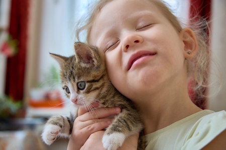 A Joyful Child Embracing a Cute and Playful Kitten in a Heartwarming Moment of Blissの写真素材
