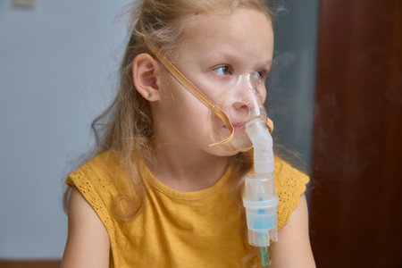 The sick girl is breathing and being treated with a nebulizer.の写真素材