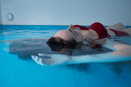 A young woman is swimming relaxed in a small pool.の写真素材