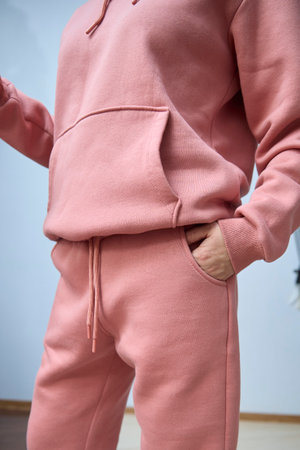 Pink hoodie and sweatpants set shown in close-up, highlighting the soft fabric texture and casual style. Hand casually placed in pocket, suggesting comfort and relaxation.の写真素材