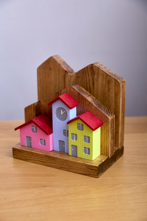 Colorful wooden house model featuring a central clock tower. This decorative item adds charm with its bright roofs and windows, ideal for home or office decor.の写真素材