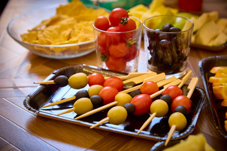Colorful vegetable skewers featuring cherry tomatoes, olives, and other fresh ingredients on a table. Perfect for party snacks or healthy appetizers, showcasing vibrant and delicious food options.の写真素材