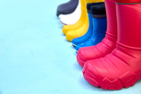 Colorful rubber boots lined up in a row on a blue surface. Emphasizing different styles and colors, this image captures the essence of outdoor fashion and practical footwear.の写真素材