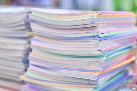 A close-up image of a stack of notebooks featuring pastel-colored pages. The neatly organized...