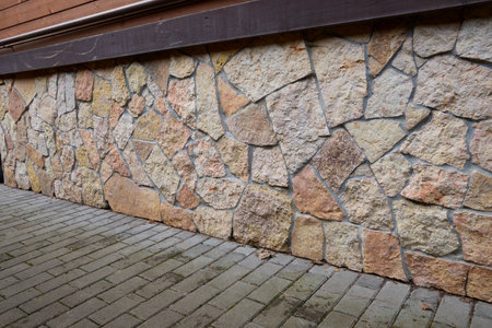 Close-up view of a rustic stone wall showcasing a variety of natural textures and patterns. The...