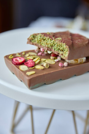 Dubai chocolate. Delicious fractured chocolate bar, speckled with freeze- dried raspberries and refreshing pistachio crumble, evokes indulgence, sweetness, and a vibrant burst of flavor, perfect for patisseries or festive food ads.の写真素材
