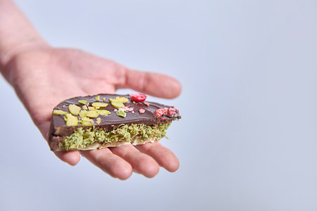 Dubai chocolate. Delicacy awaits, held open in a welcoming palm, a sweet, textured confection promises indulgence, perfect for cafes, dessert ads, or food blogs.の写真素材