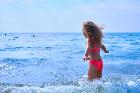 Summer vacation, a happy smiling little girl splashing in the seaの写真素材