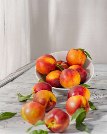 Nectarine is a subspecies of common peach, the fruit of which is characterized by a smooth skin, like a plum. Scattered on the table. Harvesting.Selective focus.の写真素材