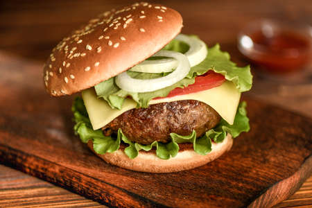 Homemade beef burger with cheese, tomato and salad on wooden background.の写真素材