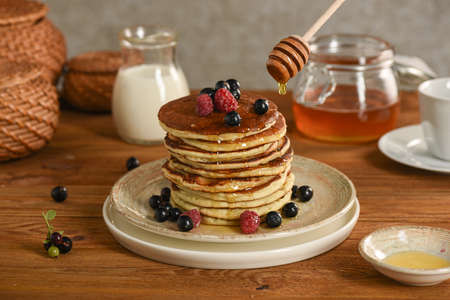 American pancakes with honey and cream. Black currant, raspberry, blackberry sprinkled with berries. Selective focusの写真素材