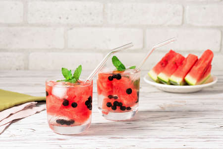 Summer watermelon cocktail with ice and mint leaves. Cold refreshing organic soft drink on white wooden backgroundの写真素材