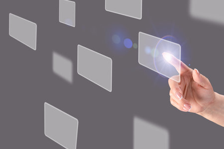 Fingertip interacting with transparent digital interface, displaying floating blank interactive screens against dark gray backdrop representing cutting edge technological innovationの写真素材