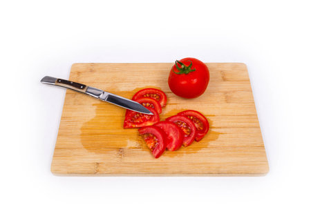 Tomato on cutting board with knifeの写真素材