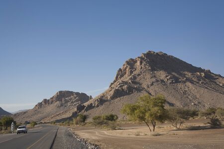 Desert landscape in Oman, mountains, trees and blue sky, no body. Road, travel by car.の写真素材