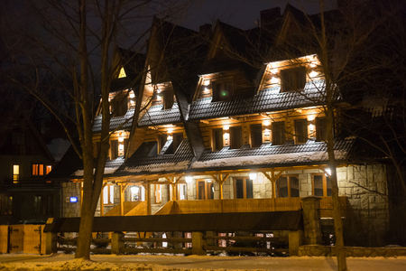 POLAND, ZAKOPANE - JANUARY 03, 2015: Traditional wooden cottage house on the street in Zakopane. Town known as the winter capital of Poland. It is a popular destination for mountaineering, skiing, and qualified tourism.のeditorial素材