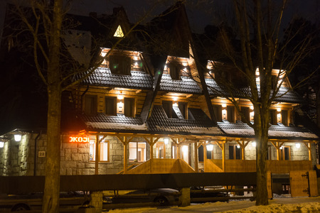 POLAND, ZAKOPANE - JANUARY 03, 2015: Traditional wooden cottage house on the street in Zakopane. Town known as the winter capital of Poland. It is a popular destination for mountaineering, skiing, and qualified tourism.のeditorial素材
