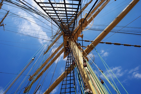 Steel masts of a sailing ship with the lowered sails with blue sky on the background.の写真素材