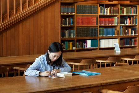 LEUVEN, BELGIUM - SEPTEMBER 05, 2014: Unknown young student girl is sitting with book in the library...