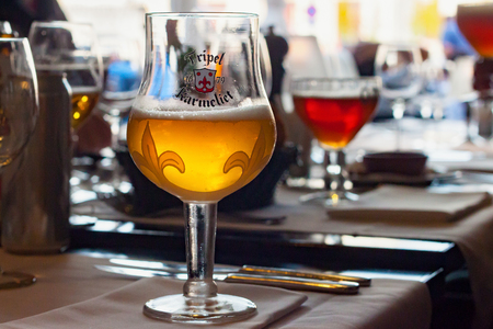LEUVEN, BELGIUM - SEPTEMBER 05, 2014: Original glass of Tripel Karmeliet beer in one of the restaurants in the Leuven. Is a golden Belgian beer with high alcohol by volume brewed by Brouwerij Bosteelsのeditorial素材