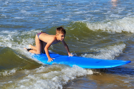 ZELENOGRADSK, KALININGRAD REGION, RUSSIA - JULY 29, 2017: Unknown boy on surfboard resting and learning of surfing on the blue waves of the Baltic Sea at summer time.のeditorial素材