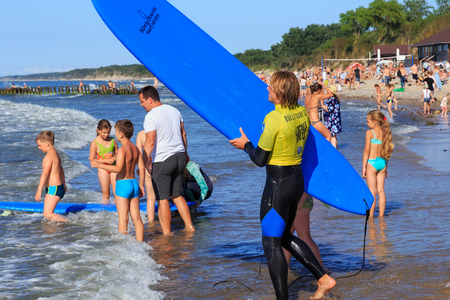 ZELENOGRADSK, KALININGRAD REGION, RUSSIA - JULY 29, 2017: Unknown surfer with surfboard standing on a sandy beach on the Baltic Sea coast in famous resort Zelenogradsk at summer time.のeditorial素材