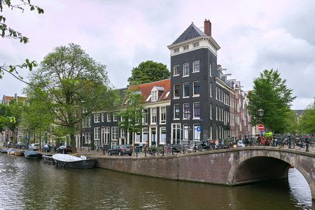 AMSTERDAM, NETHERLANDS - JUNE 25, 2017: Old buildings near the one of the water canals in the historical part of Amsterdam.のeditorial素材