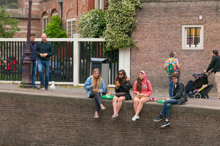 AMSTERDAM, NETHERLANDS - JUNE 25, 2017: Group of unknown young women are eating fast food on the canal banks in the historic part of Amsterdam.のeditorial素材