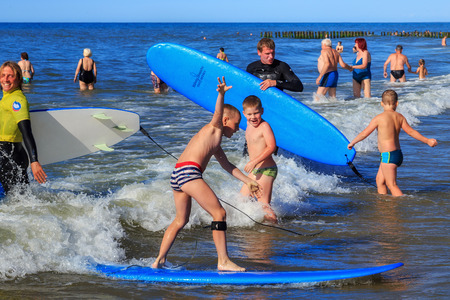 ZELENOGRADSK, KALININGRAD REGION, RUSSIA - JULY 29, 2017: Children resting and learning of surfing with professional instructors on the blue waves of the Baltic Sea at summer time.のeditorial素材
