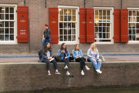 AMSTERDAM, NETHERLANDS - JUNE 25, 2017: Group of unknown young women are smoking marijuana on the canal banks in the historic part of Amsterdam.のeditorial素材
