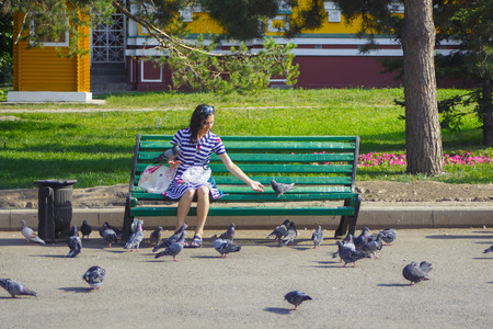 ALMATY, KAZAKHSTAN - JULY 27, 2017: Unknown woman feeding pigeons in 28 Panfilov city park in Almaty. The town is the largest city in Kazakhstan.のeditorial素材