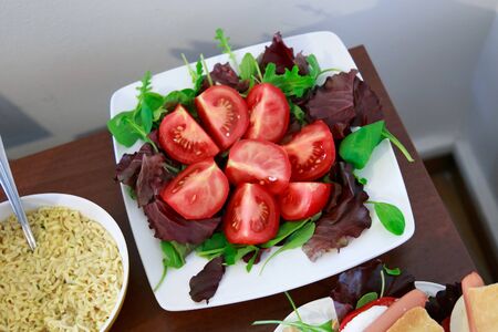 Plate with tomato and arugula salad for a breakfast. As well as a cup of instant noodle soup.の写真素材