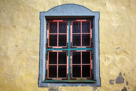 Window with a pink frame in the wall of an old traditional historical estonian house.