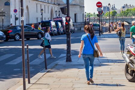 PARIS, FRANCE - JUNE 23, 2017: Unknown young girl in blue jeans and a t-shirt walking down the pavement in the center of Paris.のeditorial素材